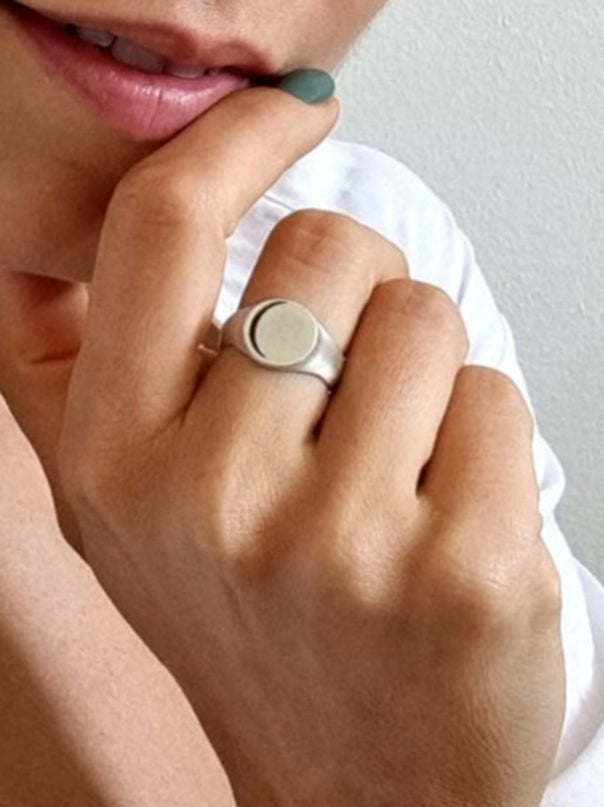 Hemi & Zo 18k sterling silver Moon Phase ring on a woman’s hand, showing her lips and green nail polish