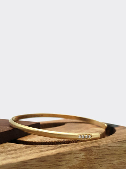 Hemi & Zo gold bangle with four diamonds, symbolizing cherished family members or personal milestones, showcased on  a hand made wooden box