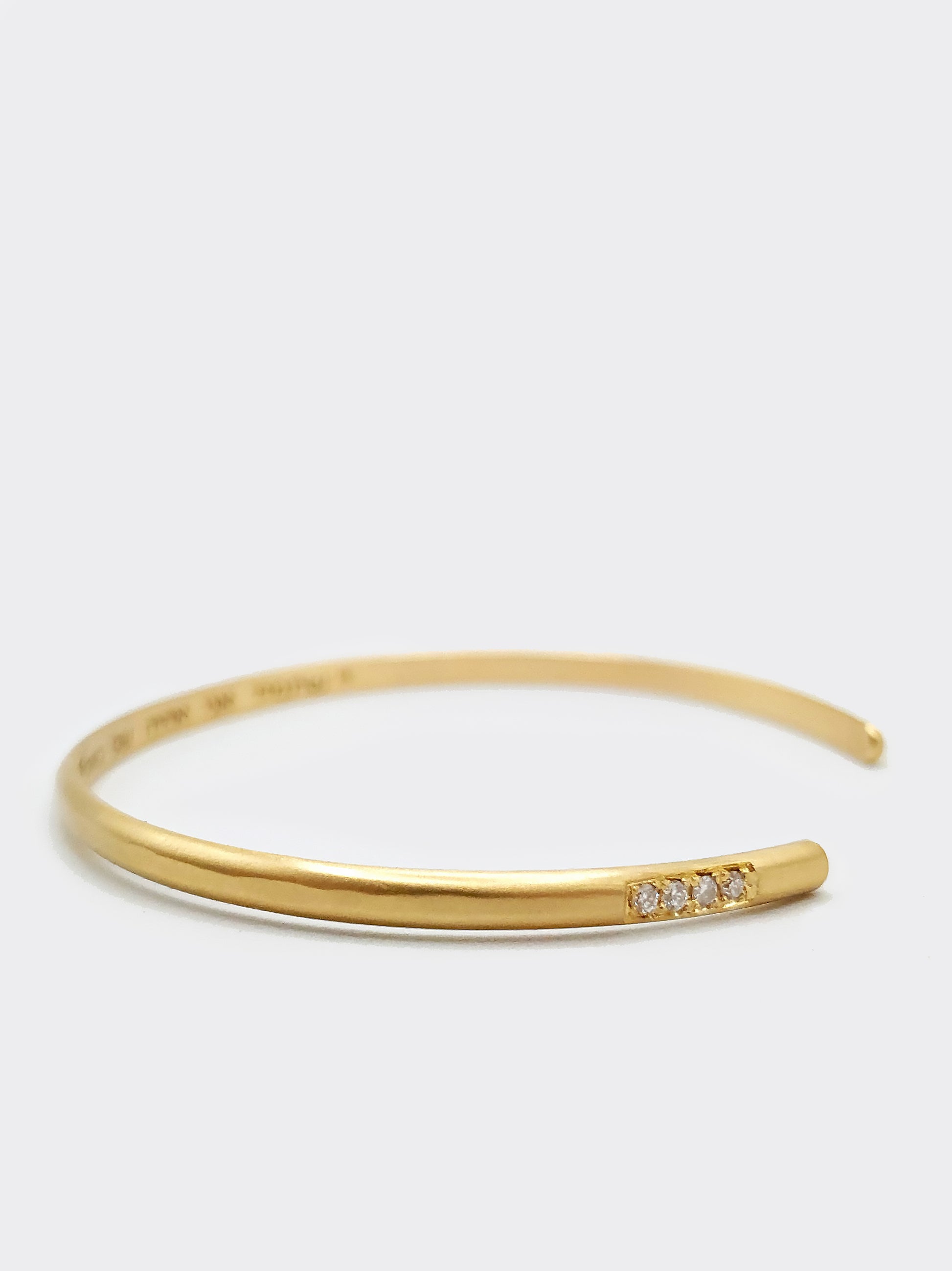 Hemi & Zo gold bangle with four diamonds, symbolizing cherished family members or personal milestones, showcased on a neutral backdrop