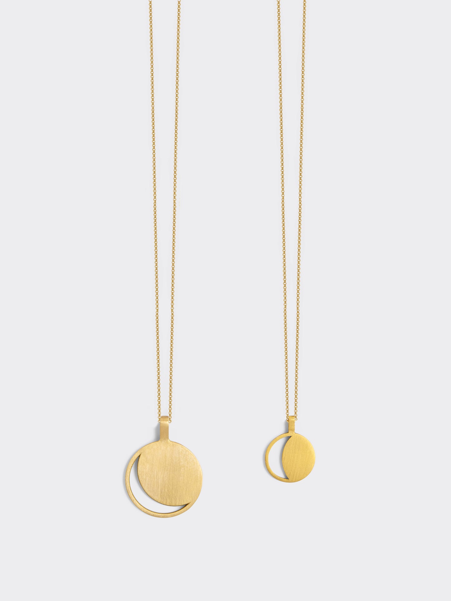 Two Hemi & Zo gold Moon Phase necklaces, one with a large pendant, one with a small pendant, presented against a white background