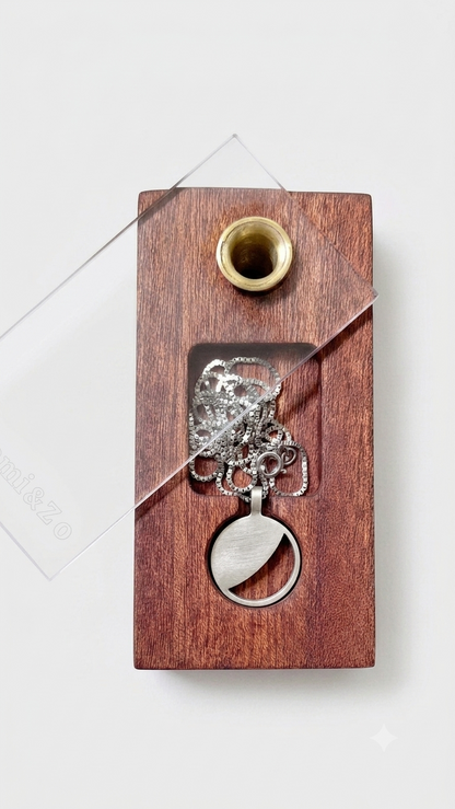Silver necklace with a moon phase pendant in a wooden box against a light gray background