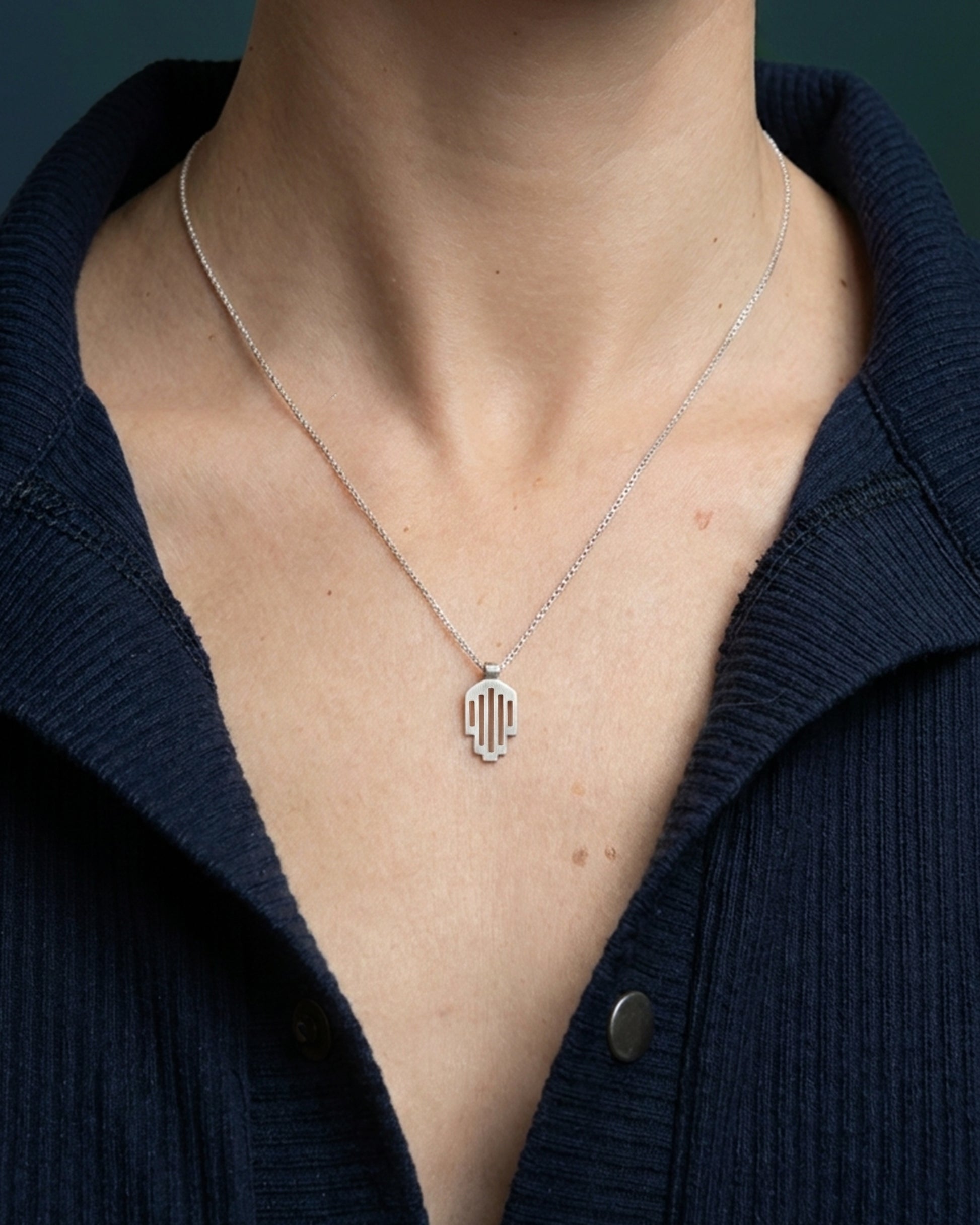 Model torso wearing a sterling silver Hemi and Zo hamsa pendant necklace