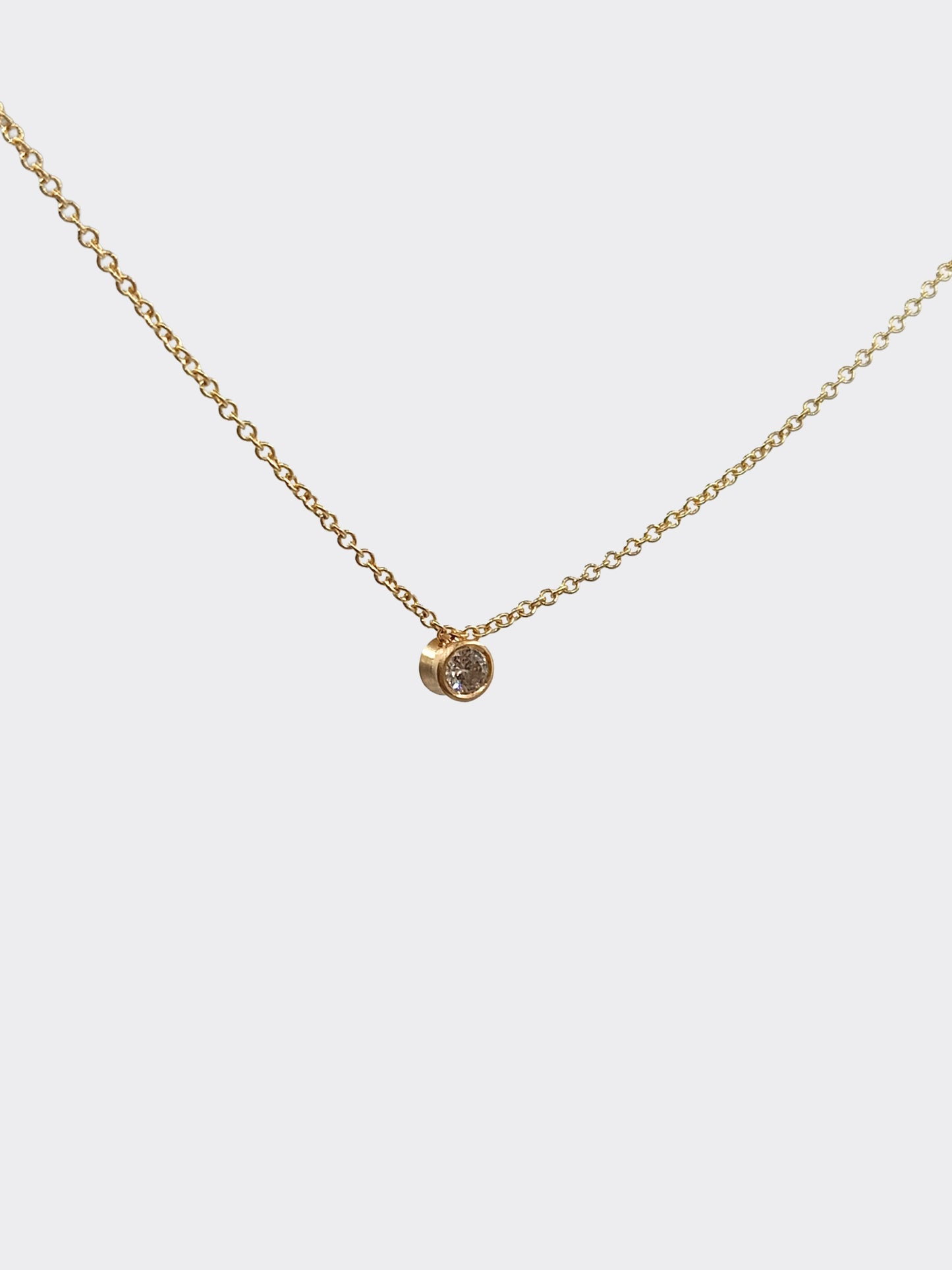 Gold duo necklace with a small diamond pendant on a light gray background
