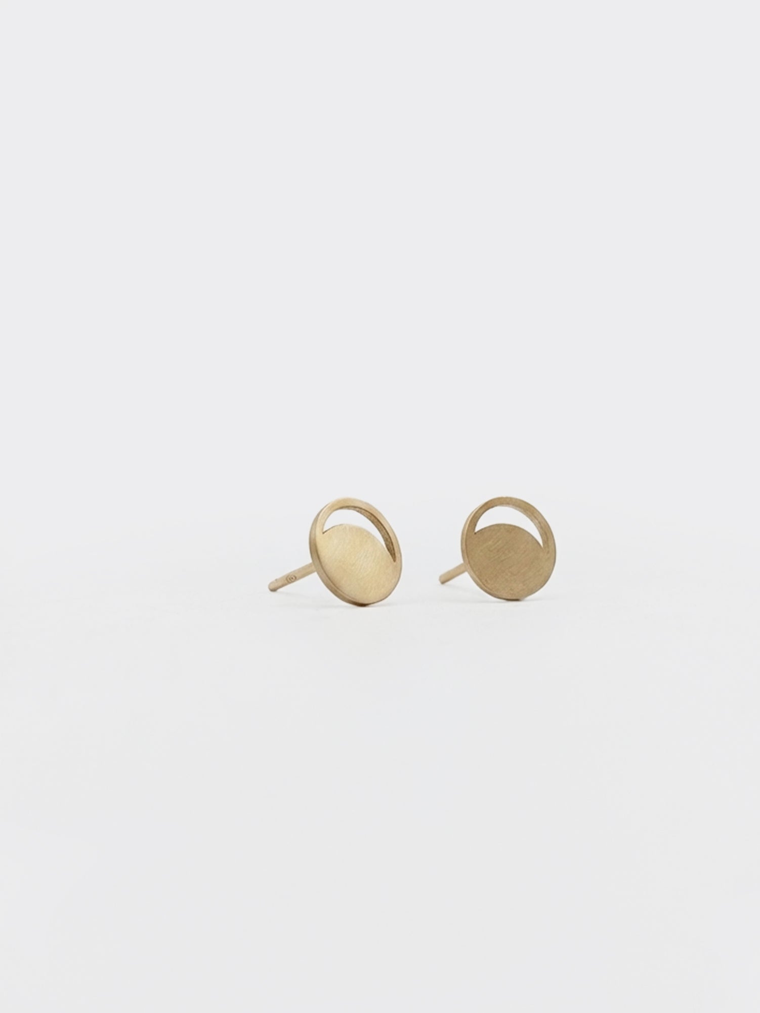 Pair of gold moon phase earrings on a light gray background