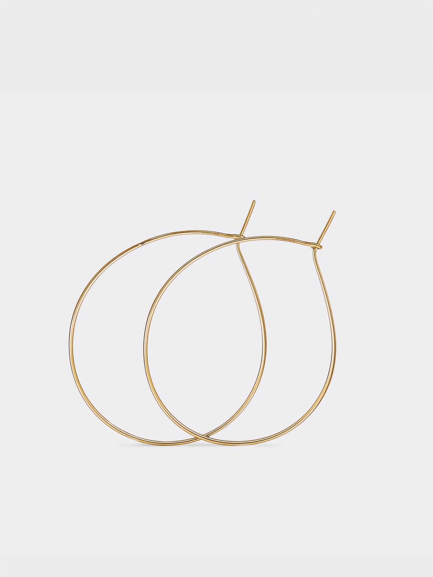 Gold teardrop hoop earrings on a light gray background
