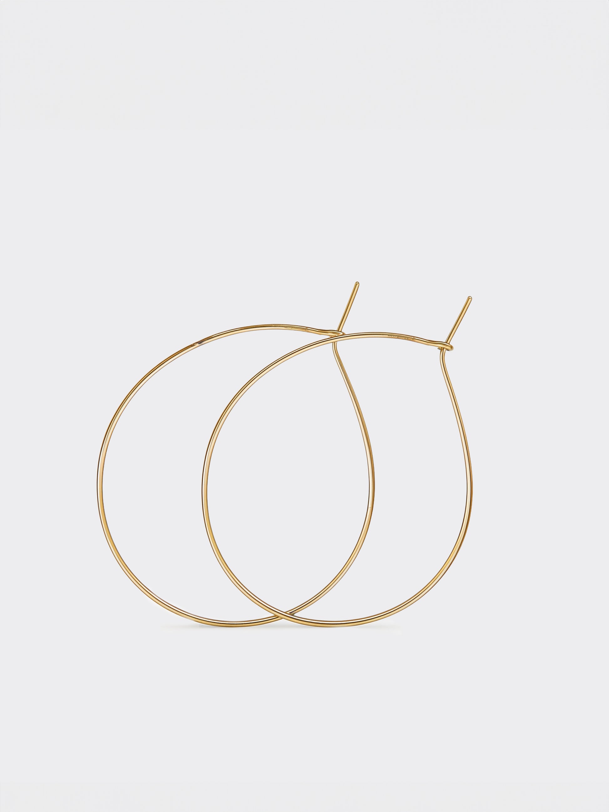 Gold teardrop hoop earrings on a light gray background